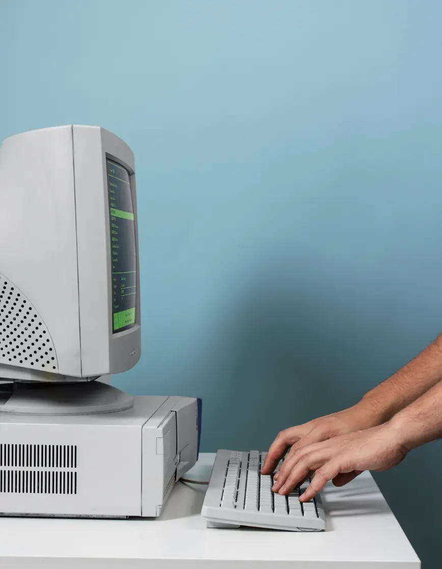 Person typing on vintage CRT computer with green-on-black terminal interface